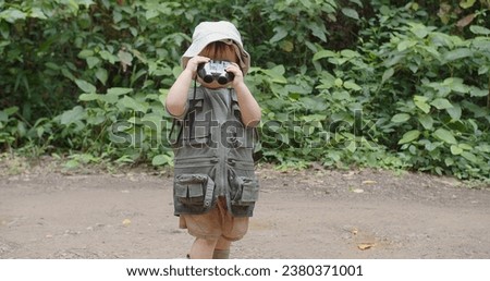 Happy Tourist cute little Asian toddler daughter kid girl using binoculars watching animals in the forest natural background, adventure explorer camping travel trip Learning about Nature