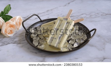 Delicious of Vanilla Cookie flavor of Popsicle Ice cream on iron tray with ice shards at marble table and white background. Two Stick Ice cream with vanilla cookie flavor. light. Selective Focus