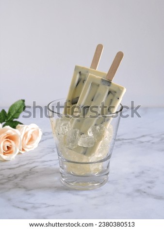 Delicious of Vanilla Cookie flavor of Popsicle Ice cream served in clear glass at marble table on white background. Stick Ice cream with vanilla cookie flavor. light. Selective Focus.