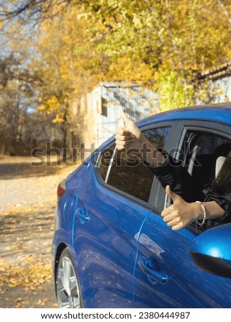 Woman inside car with thumb up gesture.