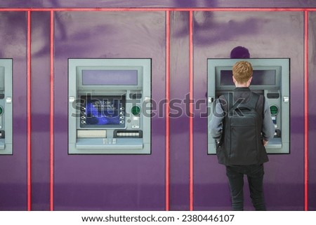 A unidentified man withdrawing cash from a cash machine 