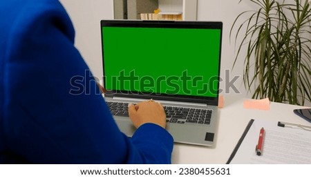 Woman sitting working on laptop with mock up green screen chroma key display. Freelancer using isolated laptop browsing on internet for social media advertising.