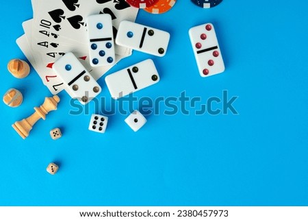 Items for playing chess, poker and domino on blue background studio shot