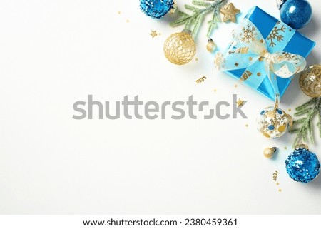Top view Christmas gift with ribbon bow and blue and gold Xmas decorations, confetti isolated on white background. Happy New Year greeting card design.