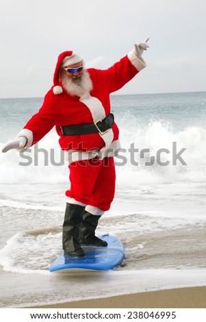 Surfing Santa Claus. Santa Claus rides on his surfboard as he rides the waves of the ocean blue. Santa Loves Sports the beach and the outdoors. Santa loves to surf on his surfboard as much as he can