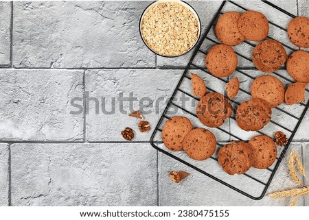 Homemade oatmeal cookies with chocolate chips and gluten free nuts on a cooling rack on concrete background,modern bakery concept with ears of corn.Healthy breakfast with ingredients,top view