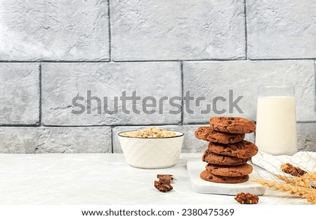 Freshly baked homemade oatmeal cookies with chocolate chips and gluten free nuts with ears on concrete background,modern bakery and grain food concept.Healthy breakfast with ingredients,