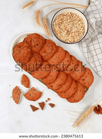 Freshly baked homemade oatmeal cookies with chocolate chips and gluten free nuts with ears on concrete background,modern bakery and grain food concept.Healthy breakfast with ingredients,top view,