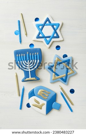 Gingerbread cookies with Jewish symbols and candles on white wooden background, top view