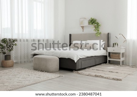 Stylish bedroom interior with large comfortable bed, ottoman and bedside table Royalty-Free Stock Photo #2380487041