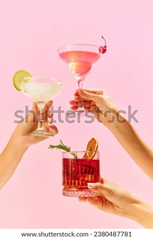 Poster. Variations of alcohol drinks. Capturing hands with funky cocktail glasses, each hosting a uniquely colorful drink, set against colorful studio background. Concept of party, mix. Copy space Royalty-Free Stock Photo #2380487781