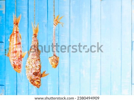 The three cooking stages of a red mullet: raw, fried with its own scales, and already eaten.