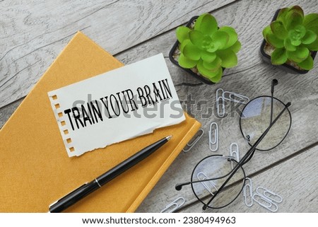 train your brain. text on torn paper for writing. on a yellow notepad. plant in the pot