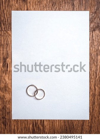 Simple flat lay mockup of a pair of wedding rings on a blank textured paper and wooden table background