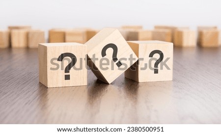 three wooden blocks with question marks over a grey background with copy space
