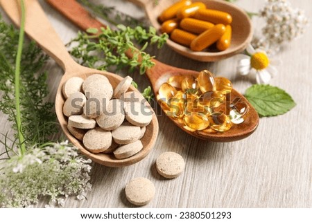 Different pills, herbs and flowers on wooden table, closeup. Dietary supplements Royalty-Free Stock Photo #2380501293