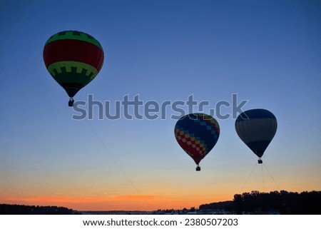 Colorful Air Balloons Levitating Over the Ground Outdoors Against Clear Blue Skies At Twilight. Horizotal Shot