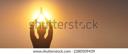 silhouette of a woman raising her hands, praying for God's blessings in the light of sunset or sunrise, practicing yoga and meditation in nature, concept of religion, freedom and spirituality