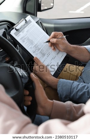 Driving school. Student passing driving test with examiner in car, closeup Royalty-Free Stock Photo #2380510117