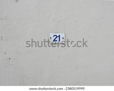           A metal plate with a number of twenty one, attached to a white wall.