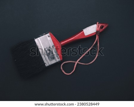 Paint brush, red handle, on a black background