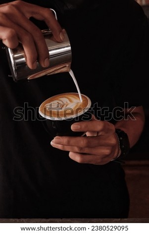 Barista showing his skill for making the latte art. Selective focus and blurry background. 
