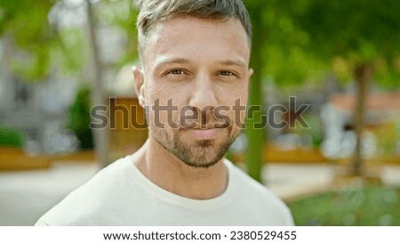 Young man standing with serious expression at park