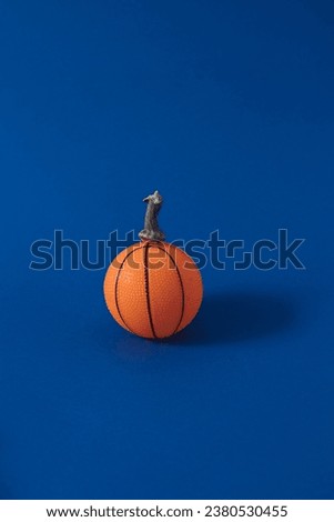 Orange basketball and pumpkin handle on a blue background. Minimal Halloween concept.