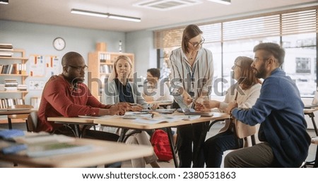 Grown Up Men and Women Working in Groups for an Assignment in Specialty Development Center. Adult Classmates Working on a Team Assignment, Young Female Teacher Explaining the Exercise Goals Royalty-Free Stock Photo #2380531863