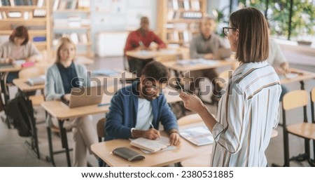 Grown-Up Men and Women Getting Self-Improvement Course in College. Adult Class Writing Down Notes in Notebook and Using Laptop Computers. Tutor Standing in Front of Them and Giving a Lecture Royalty-Free Stock Photo #2380531885