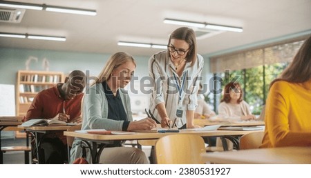 Helpful Young Teacher Talking with a Middle-Aged Female, Helping to Find a Solution for a Test Course Assignment. Multiethnic Women and Men of Different Age Acquiring New Academic Skills in Classroom Royalty-Free Stock Photo #2380531927