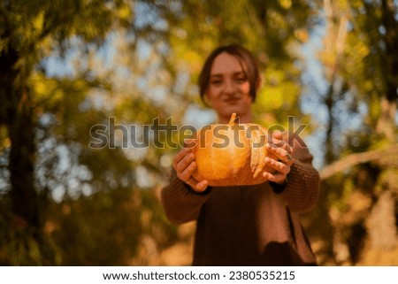 portrait of a woman with a pumpkin in the autumn forest, young woman holding an orange pumpkin in her hands, Halloween concept