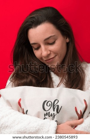 Caucasian girl hugging a Christmas pillow on red background