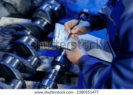 Serviceman with tablet inspection diesel engine motor of lorry and checking semi truck on background repair garage. Royalty-Free Stock Photo #2380551477