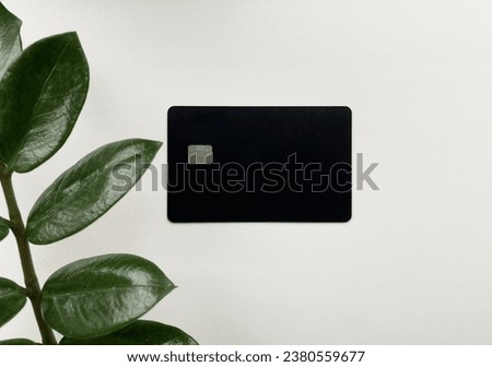 Black card with a green leaf on light background. Business photo. Credit card