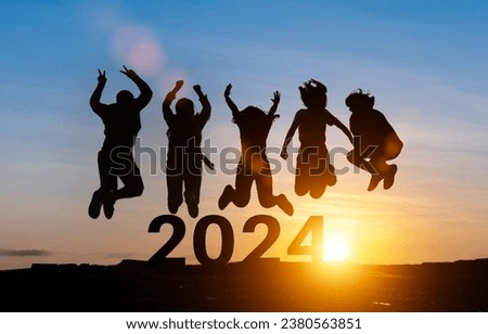 Happy group of people celebrate jump for new year 2024. concept for win victory. silhouette of friends jumps at sunset time on mountains.