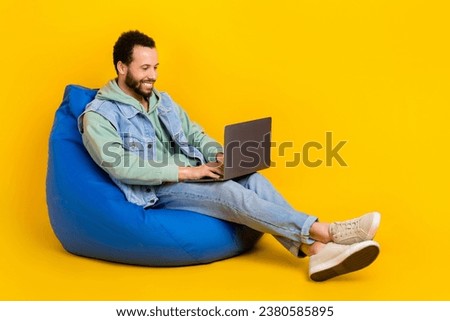 Full body length photo of freelancer worker businessman latin using netbook sit pouf smm targetolog isolated on yellow color background