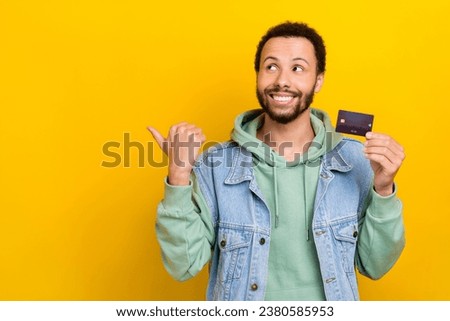 Photo portrait of attractive young guy point look empty space credit card wear trendy khaki garment isolated on yellow color background