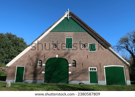 frontal view of Salland farm with green painted parts and thatched roof Royalty-Free Stock Photo #2380587809