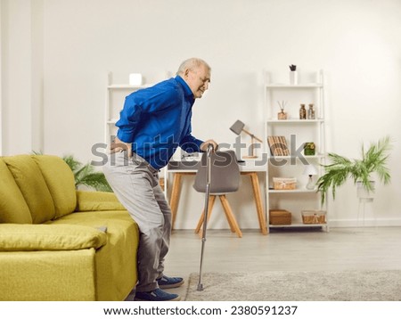 Senior man suffering from back pain at home. Elderly man with walking cane feeling pain while trying to get up from couch. Old age, medical and healthcare concept Royalty-Free Stock Photo #2380591237