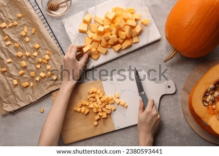Woman with knife taking piece of fresh pumpkin at light grey table, top view