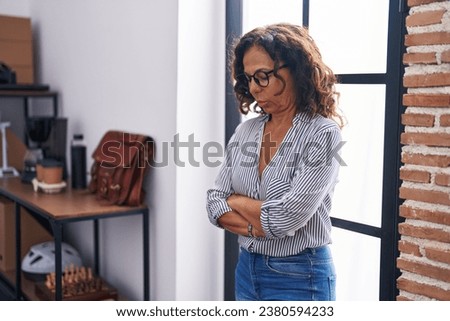 Middle age woman business worker standing with arms crossed gesture at office