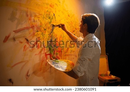 In the art studio artist man painting new picture contemporary painting he using the fingers and add some oil colour on the picture