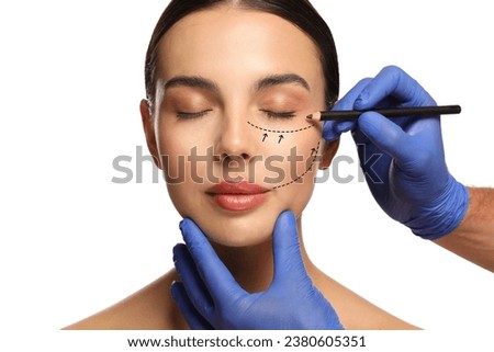 Woman preparing for cosmetic surgery, white background. Doctor drawing markings on her face, closeup Royalty-Free Stock Photo #2380605351
