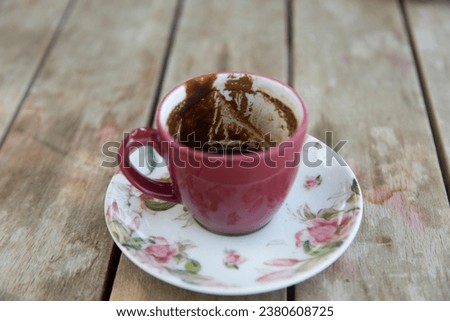 Traditional Turkish coffee fortune telling. Close-up of coffee grounds shapes in colorful coffee cup on wooden table. Royalty-Free Stock Photo #2380608725