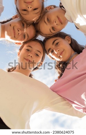 Five friends huddled in a circle, looking at the camera and smiling. Friendship and unity among girls. Friends forever. Adolescence and puberty Royalty-Free Stock Photo #2380624075