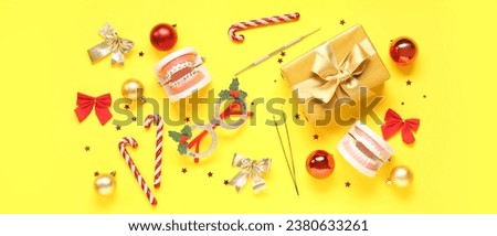 Models of jaw with dentist's tools, Christmas gift and decor on yellow background