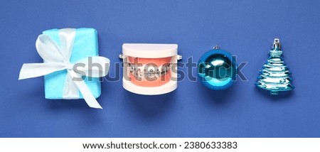 Model of jaw with Christmas gift and decor on blue background