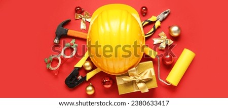 Construction tools with Christmas decor and gift on red background