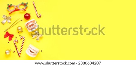 Models of jaw with dentist's tools, Christmas decor on yellow background with space for text